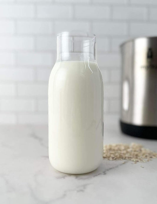 Bottle of freshly made plant-based milk on a countertop with a kitchen appliance in the background